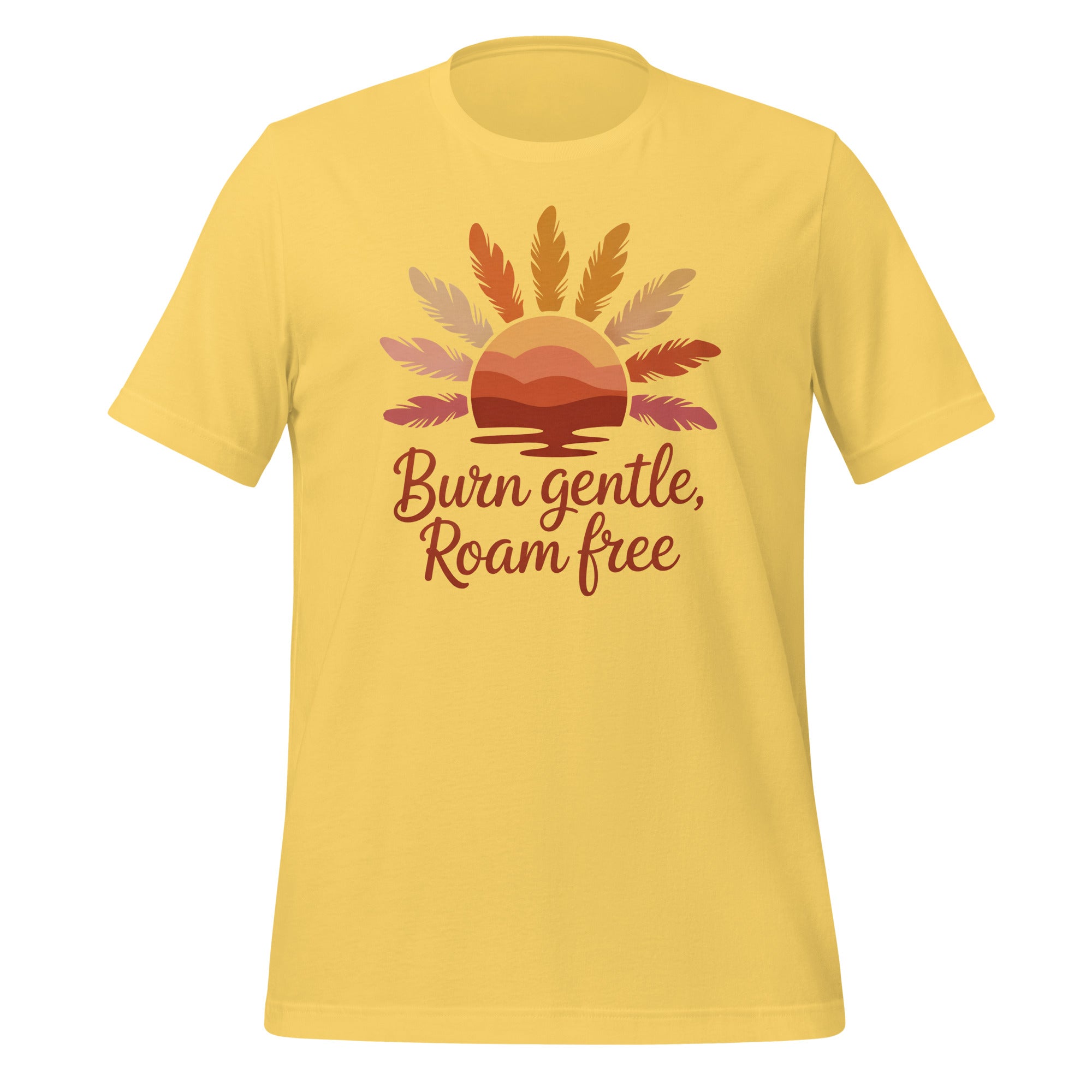 T-shirt unisexe jaune avec un design bohème d’un soleil couchant, des plumes, un paysage montagneux et le texte "Burn gentle, Roam free" en tons orangés.