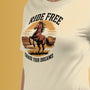 Un tee-shirt beige avec un motif de cheval cabré au coucher de soleil et l’inscription "Ride Free, Chase Your Dreams", pour HappyAndShiny.com.