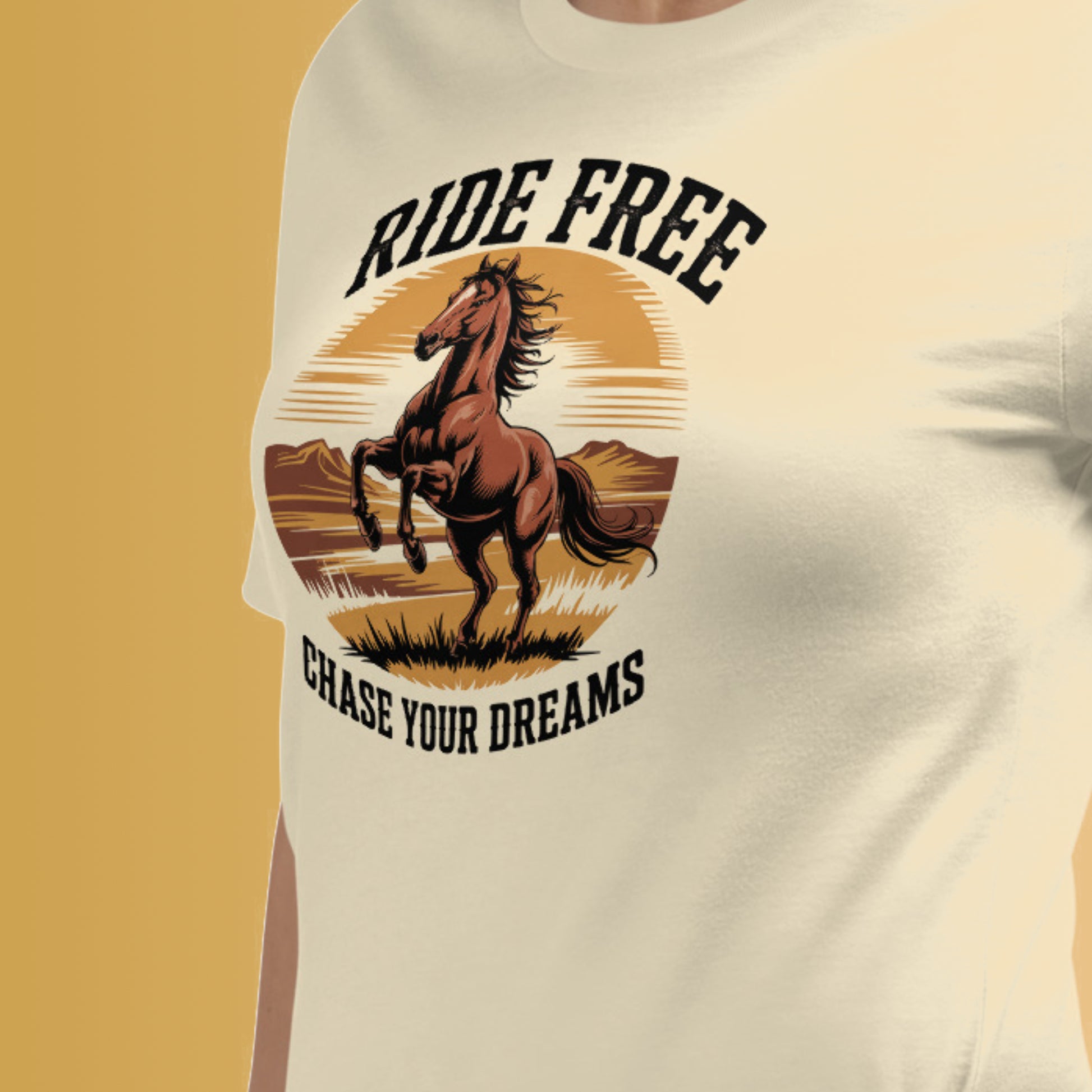 Un tee-shirt beige avec un motif de cheval cabré au coucher de soleil et l’inscription "Ride Free, Chase Your Dreams", pour HappyAndShiny.com.