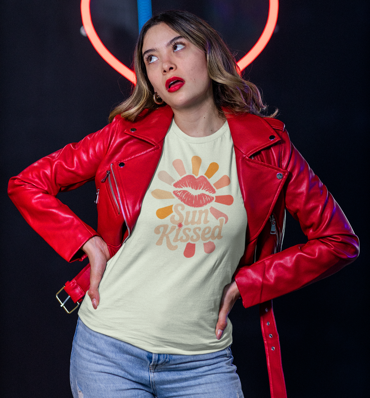 Femme en t-shirt Sun Kissed avec veste en cuir rouge devant un cœur néon
