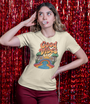 Femme en t-shirt beige Good Vibes devant un rideau de paillettes rouges