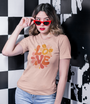 Femme en t-shirt beige Love avec lunettes rouges devant un fond à damier noir et blanc