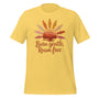 T-shirt unisexe jaune avec un design bohème d’un soleil couchant, des plumes, un paysage montagneux et le texte "Burn gentle, Roam free" en tons orangés.