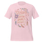 T-shirt unisexe avec un design inspirant affichant le texte "Dream Big, Start Small" (lettres blanches) entouré de plumes multicolores (rose, bleu, violet), d’un attrape-rêves et de motifs célestes.