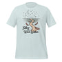 T-shirt unisexe bleu pâle avec un design bohème d’un chemin sinueux, une lune croissante, des plumes, des étoiles et le texte "Follow the Wind Within".