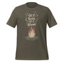 T-shirt unisexe vert kaki avec un design bohème d’un feu de camp, des flammes orangées et blanches, et le texte "Let it burn, let it bloom" avec des étoiles.