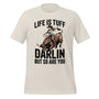 T-shirt unisexe beige avec un design western d’une cowgirl montant un taureau, texte "Life is Tuff Darlin but so are You", style robuste.