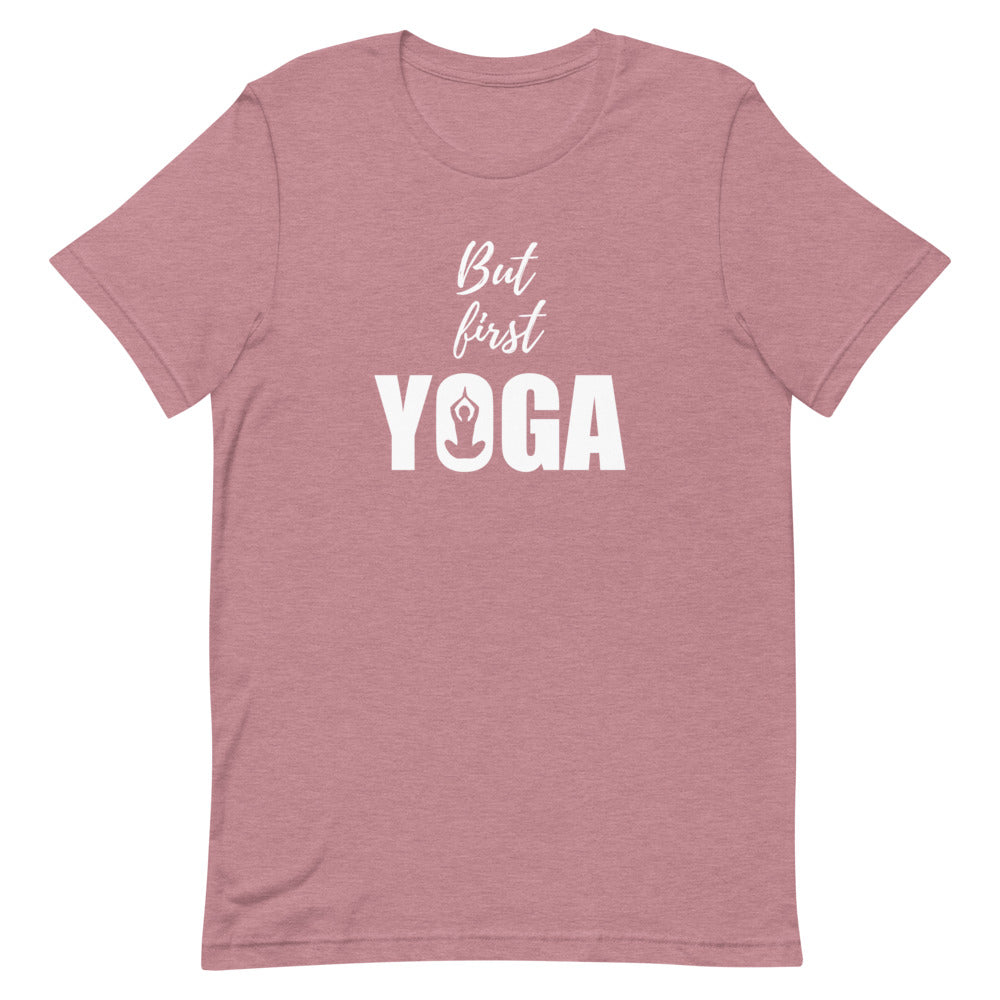 T-shirt rose poudré unisexe avec un design bohème affichant le texte "But first YOGA" en blanc, accompagné d’une silhouette méditative en position de lotus intégrée dans la lettre "O"