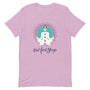 T-shirt rose poudré unisexe avec un design aligné affichant une silhouette méditative blanche en position de lotus, ornée de chakras colorés, entourée d’un mandala violet et turquoise, avec le texte "But First Yoga" en bleu foncé.