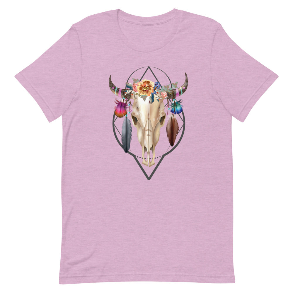 T-shirt unisexe rose pâle avec un design bohème d’un crâne à cornes orné de fleurs multicolores, plumes, perles et motifs géométriques, style spirituel.