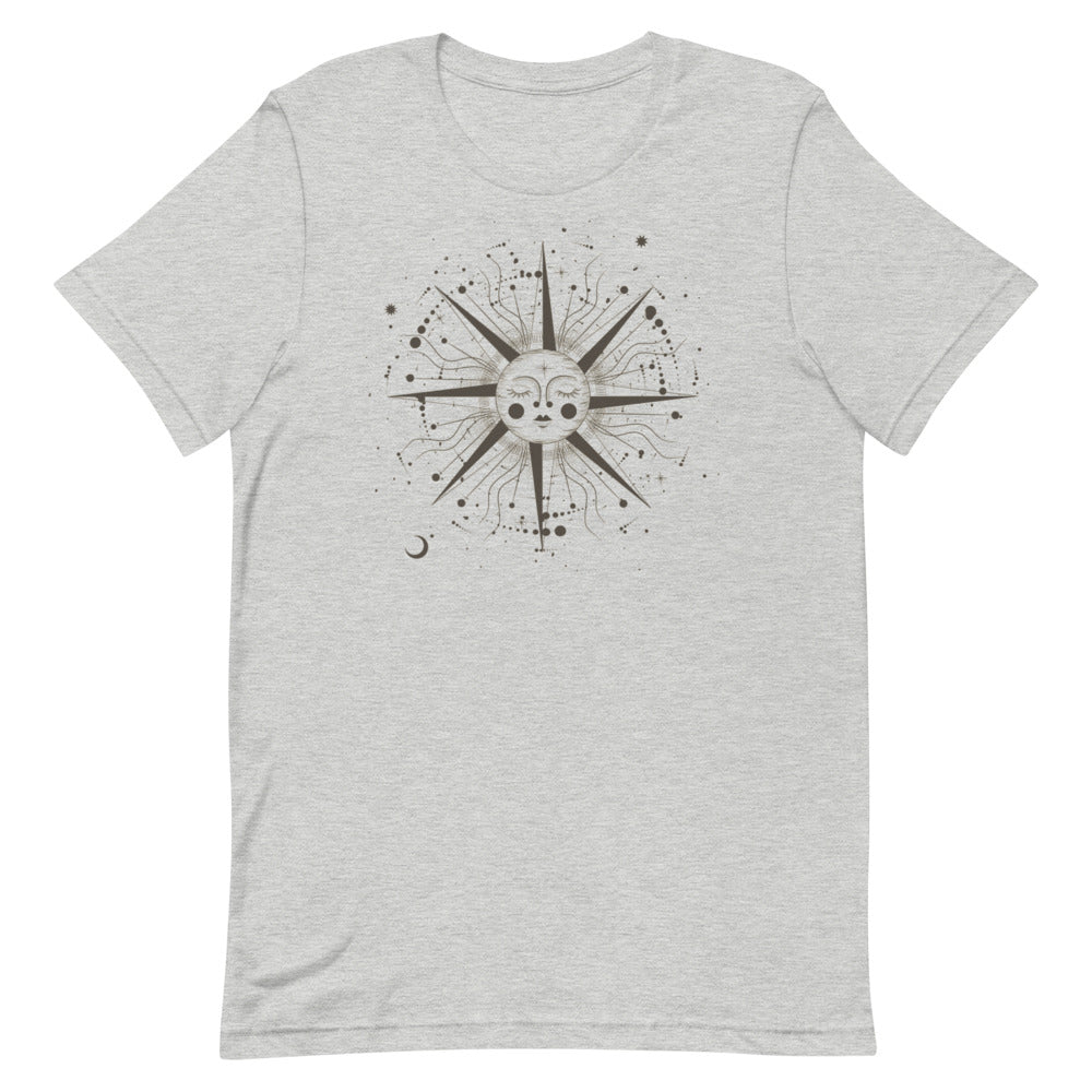 T-shirt gris clair unisexe avec un design bohème d’un soleil beige et marron orné d’un visage stylisé, entouré de motifs cosmiques comme des étoiles, des rayons et des cercles.