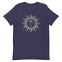T-shirt bleu marine unisexe avec un design bohème d’un soleil beige et doré orné d’un visage, entouré de rayons stylisés et de motifs subtils comme des étoiles et des croissants de lune.