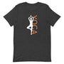 T-shirt gris foncé unisexe avec un design équilibré affichant une silhouette blanche en pose d’arbre (Vrksasana), intégrée au mot "YOGA" en lettres majuscules orange.